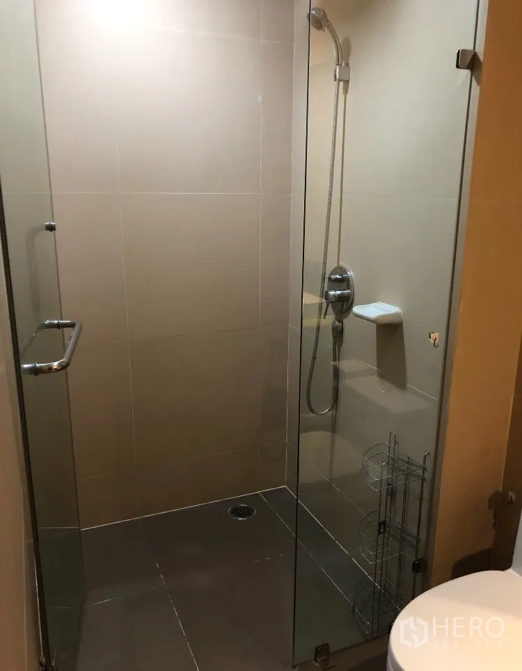 公寓 出租在Watthana, Bangkok - 瓷砖浴室，玻璃淋浴间配手持花洒。