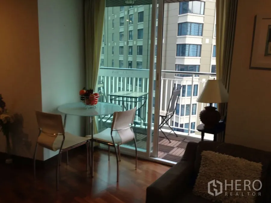 Condominium for rent in Pathum Wan, Bangkok - Living room with glass doors opening to a balcony and city view in a Pathum Wan condo.