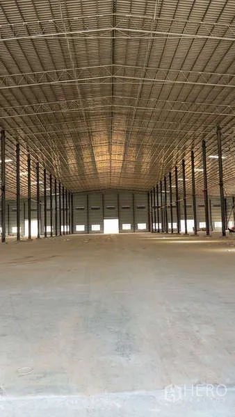 คลังสินค้า ให้เช่าในBan Bueng, Chon Buri - มุมมองสมมาตรของโกดังเพดานสูง แถวเสาเหล็กยาวและประตูม้วน