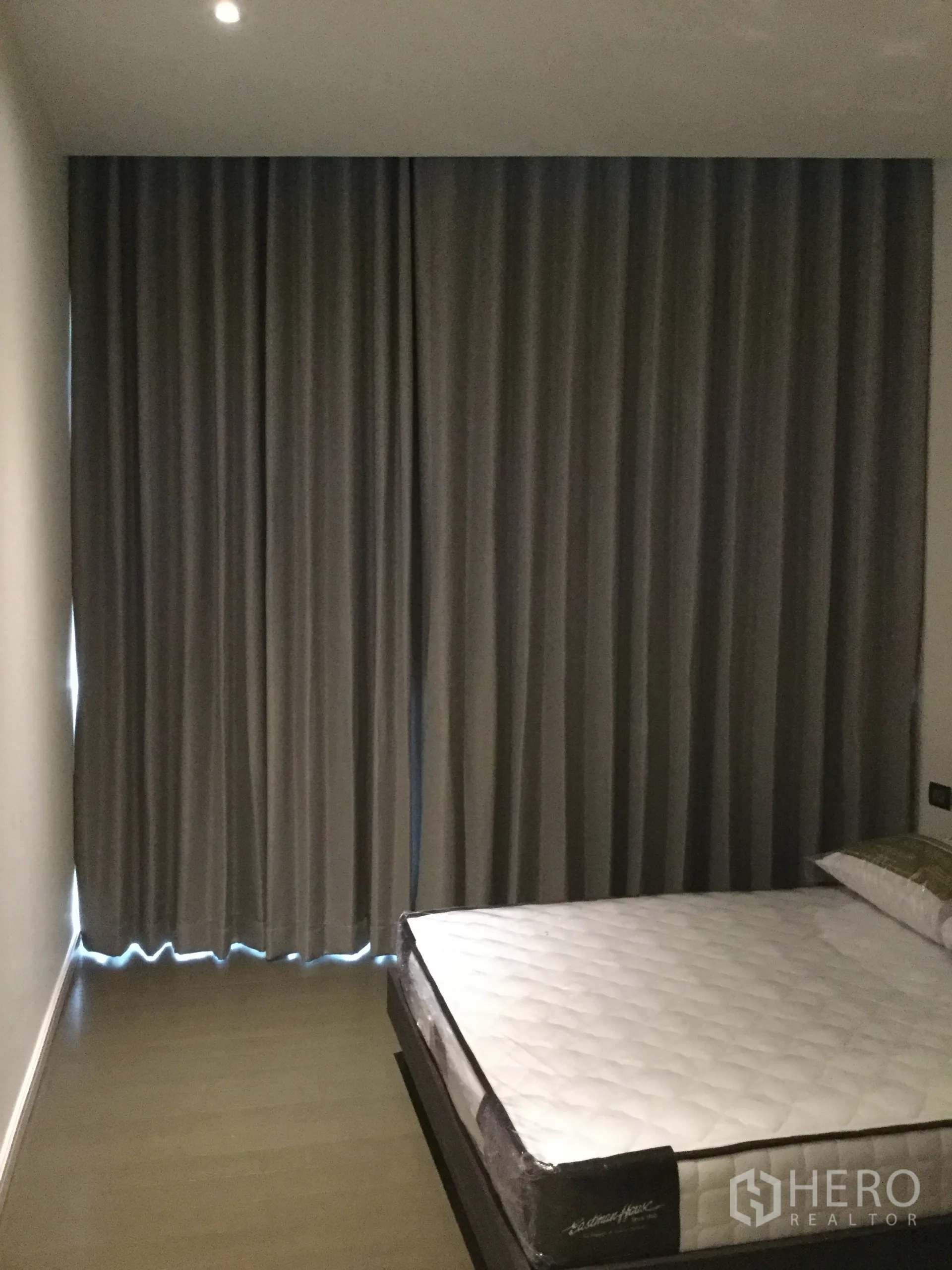 คอนโด ให้เช่าในPathum Wan, Bangkok - ห้องนอนพร้อมเตียงและผ้าม่านทึบแสง ไฟดาวน์ไลท์และพื้นไม้.