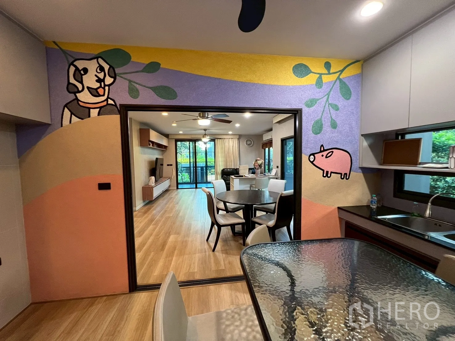 独栋房屋 for rent in Bang Kapi, Bangkok - 从茶水间望向客厅，墙面卡通壁画与餐桌。
