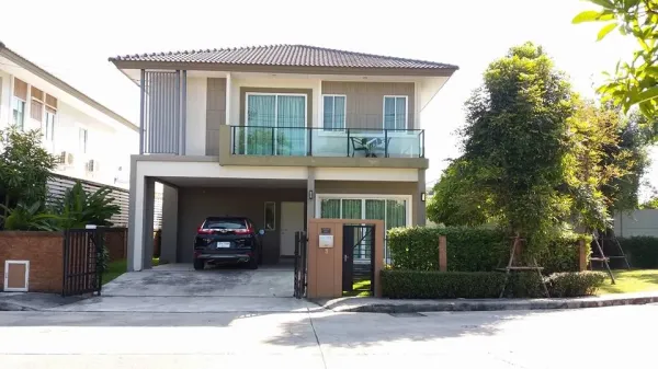 Detached House for rent in Pathum Thani - Two-storey detached house with tiled roof, glass balcony, double carport and landscaped corner garden