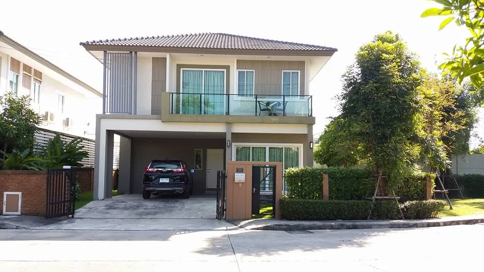 Detached House for rent in Pathum Thani - Two-storey detached house with tiled roof, glass balcony, double carport and landscaped corner garden