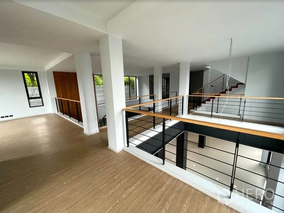 Detached House for sale in Watthana, Bangkok - Upper mezzanine with wood floors and black metal railings.