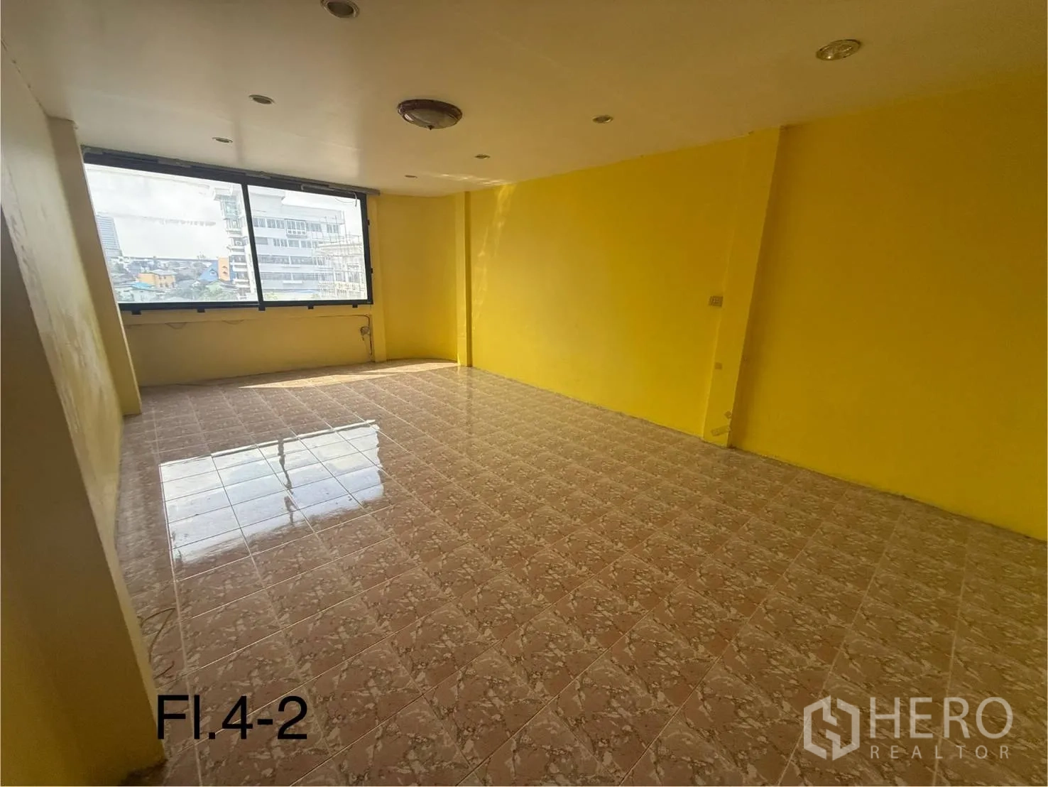 Shophouse for rent in Bang Na, Bangkok - Fourth-floor room with yellow walls, glossy floor tiles, and wide windows for natural light.