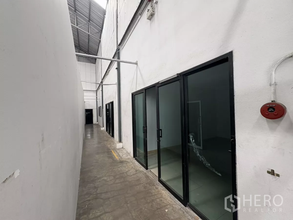 คลังสินค้า ให้เช่าในBang Phli, Samut Prakan - ทางเดินข้างโกดังติดห้องออฟฟิศกระจกบานเลื่อน และสัญญาณเตือนอัคคีภัย.