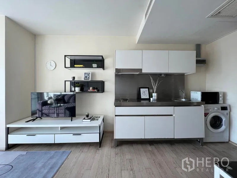 公寓 出租在Khlong Toei, Bangkok - 开放式客厅，带电视柜与白色小厨房及洗衣机