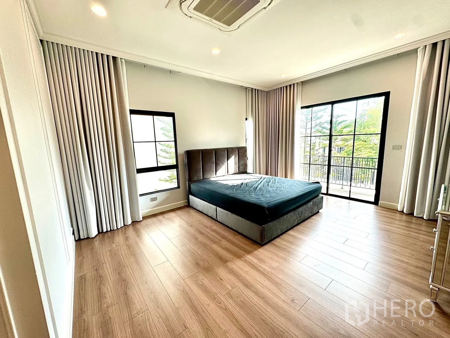 Detached House for rent in Bang Phli, Samut Prakan - Master bedroom with corner windows, balcony access and an upholstered bed.