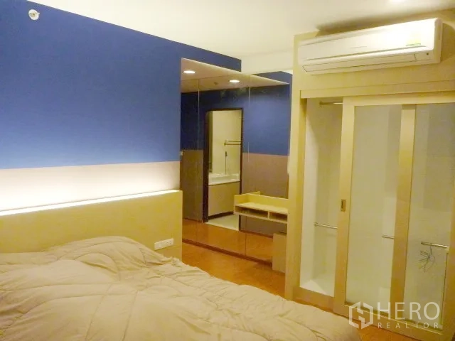 Condominium for rent in Watthana, Bangkok - Master bedroom with built-in wardrobe, wall-mounted air conditioner and vanity area.