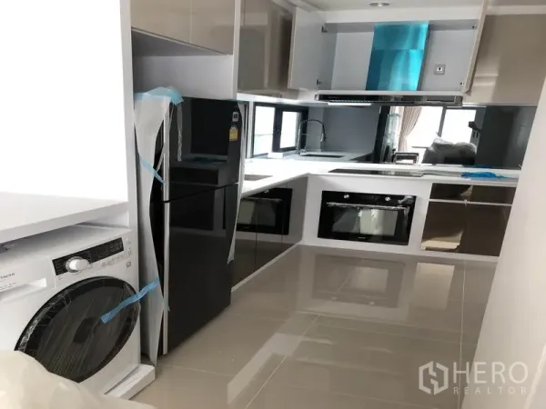 独立式住宅 出租在Prawet, Bangkok - U字型现代厨房，亮面橱柜，嵌入式烤箱，冰箱与洗衣机。