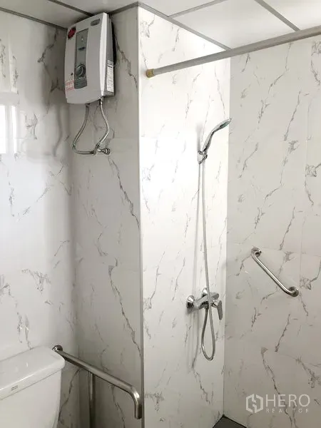 Apartment for rent in Suan Luang, Bangkok - Modern bathroom with marble-effect tiles, walk-in shower, handheld shower, water heater and safety grab bars.