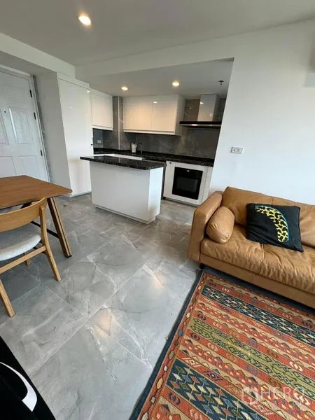 公寓 出租或出售 - 现代厨房，白色橱柜、黑色花岗岩中岛与嵌入式烤箱。