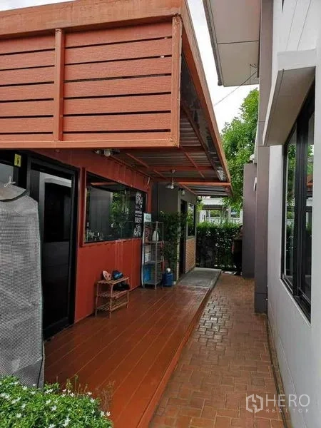 Detached House for sale in Bang Phli, Samut Prakan - Covered side terrace with red awning, tiled walkway and hedge beside the house
