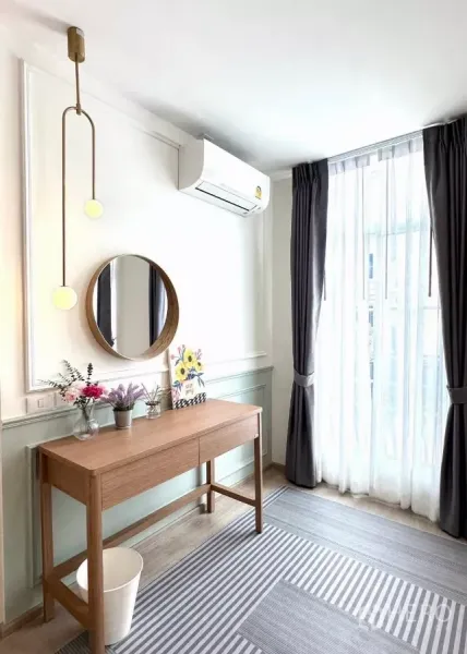 联排别墅 出租在Prawet, Bangkok - 明亮工作角，长桌、圆镜、落地窗帘与空调。