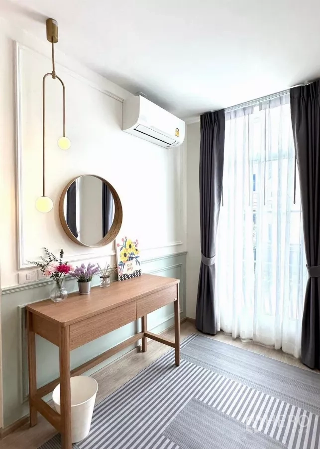 联排别墅 出租在Prawet, Bangkok - 明亮工作角，长桌、圆镜、落地窗帘与空调。