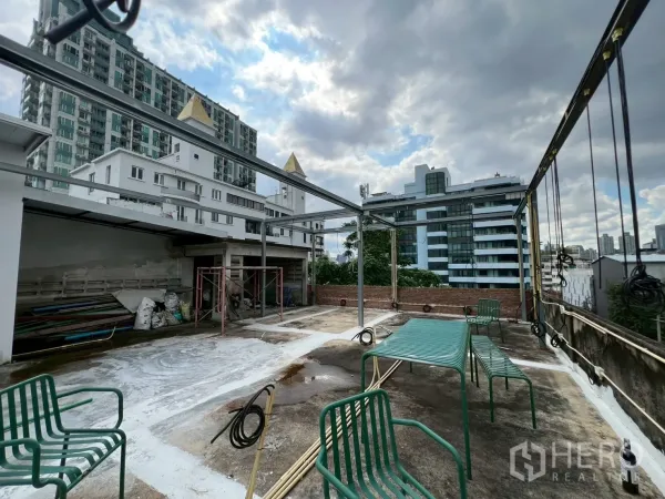 零售空间 出租在Watthana, Bangkok - 开放式屋顶平台，绿色金属桌椅与周边公寓楼