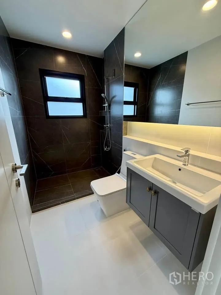 Detached House for rent in Don Mueang, Bangkok - Bathroom with dark-tiled shower zone, vanity, and toilet.