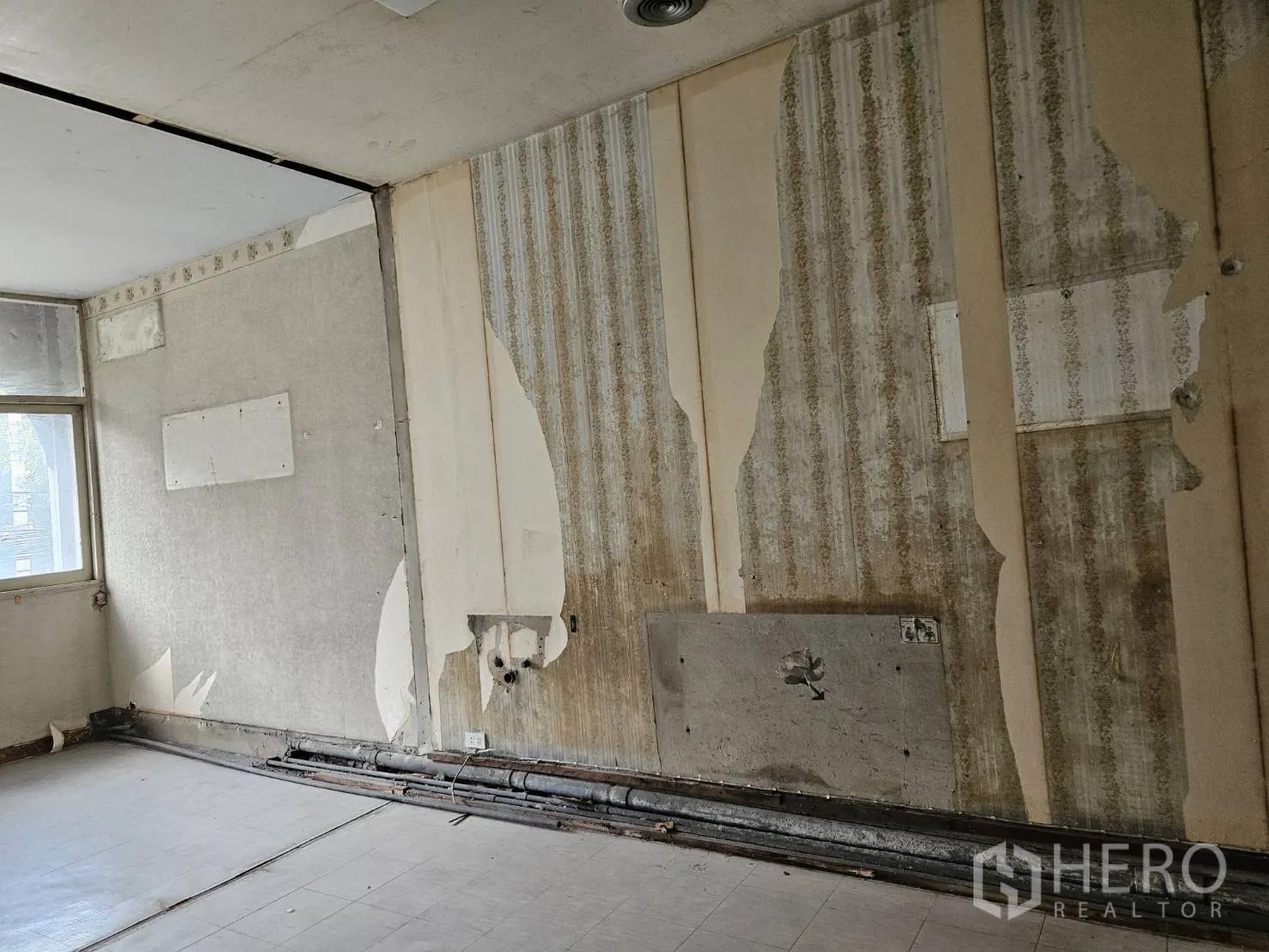 店屋 出租在Watthana, Bangkok - 室内墙面细节，可见剥落墙纸与裸露管线。