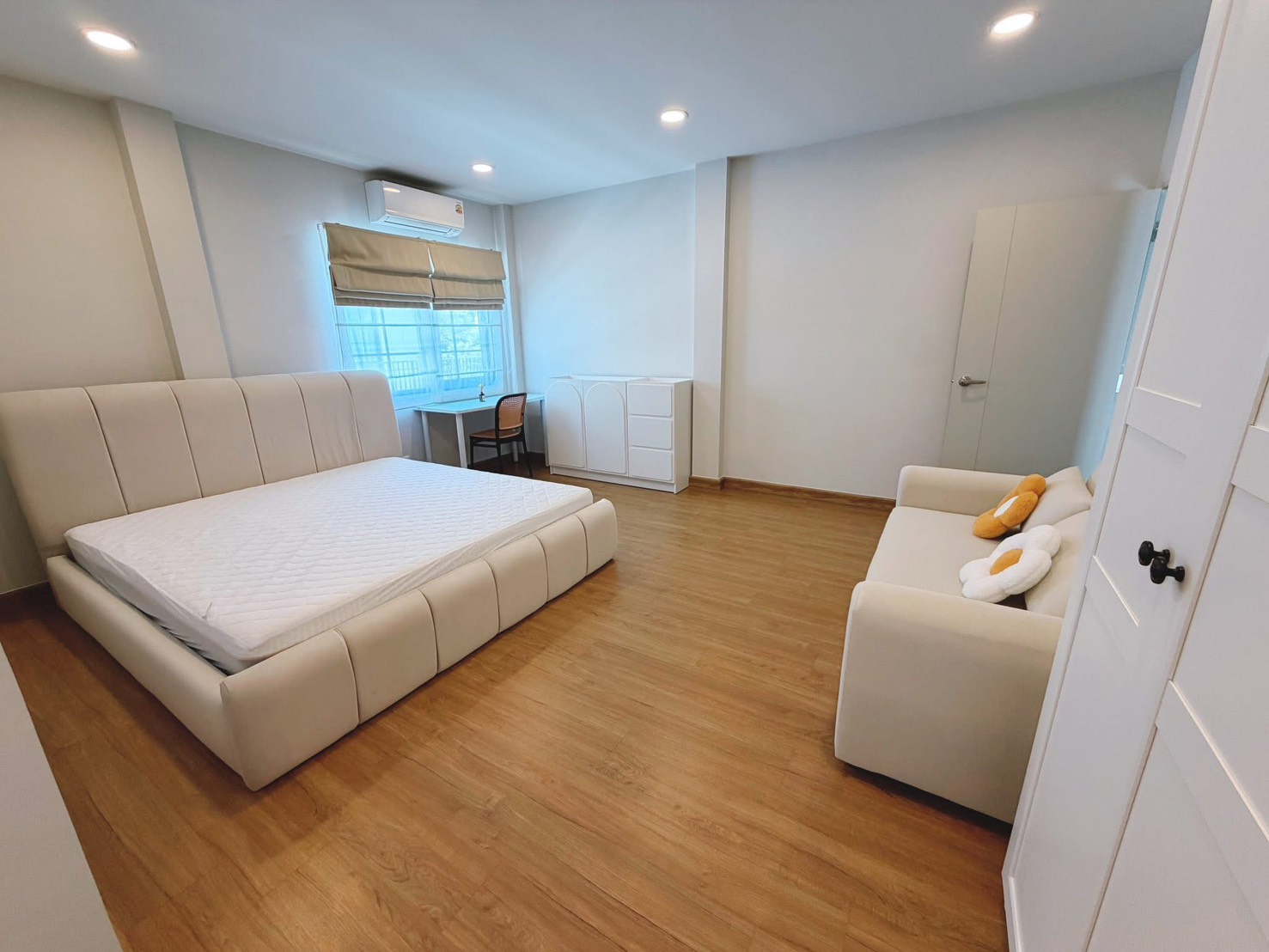 独立式住宅 出租在Bang Phli, Samut Prakan - 宽敞主卧，软包大床、沙发、书桌与木地板。