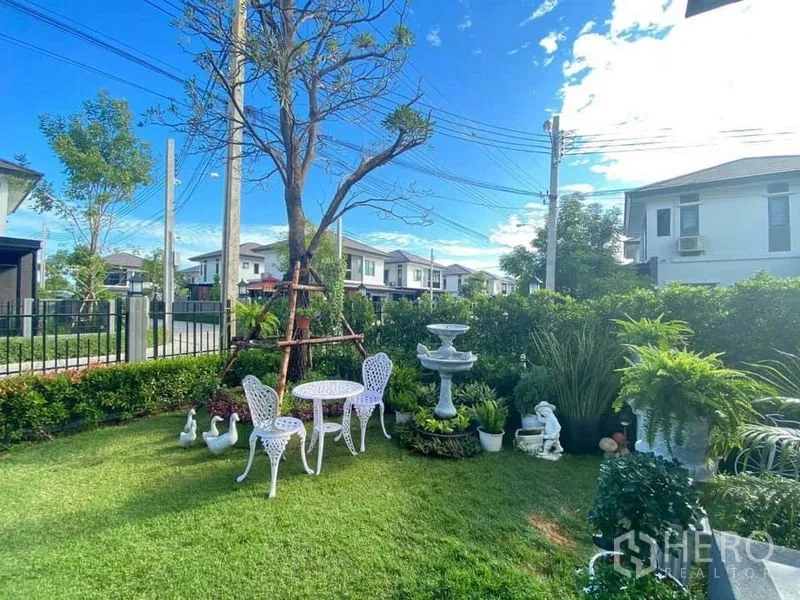 Detached House for rent in Bang Phli, Samut Prakan - Lush front lawn with white outdoor bistro set, fountain and ornamental plants.