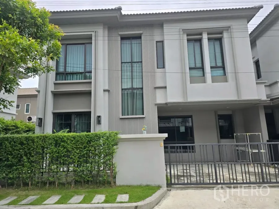 独立式住宅 出租在Khlong Luang, Pathum Thani - 两层现代独栋别墅外观，设大面积落地窗、绿篱与金属滑门，位于空銮巴吞他尼。