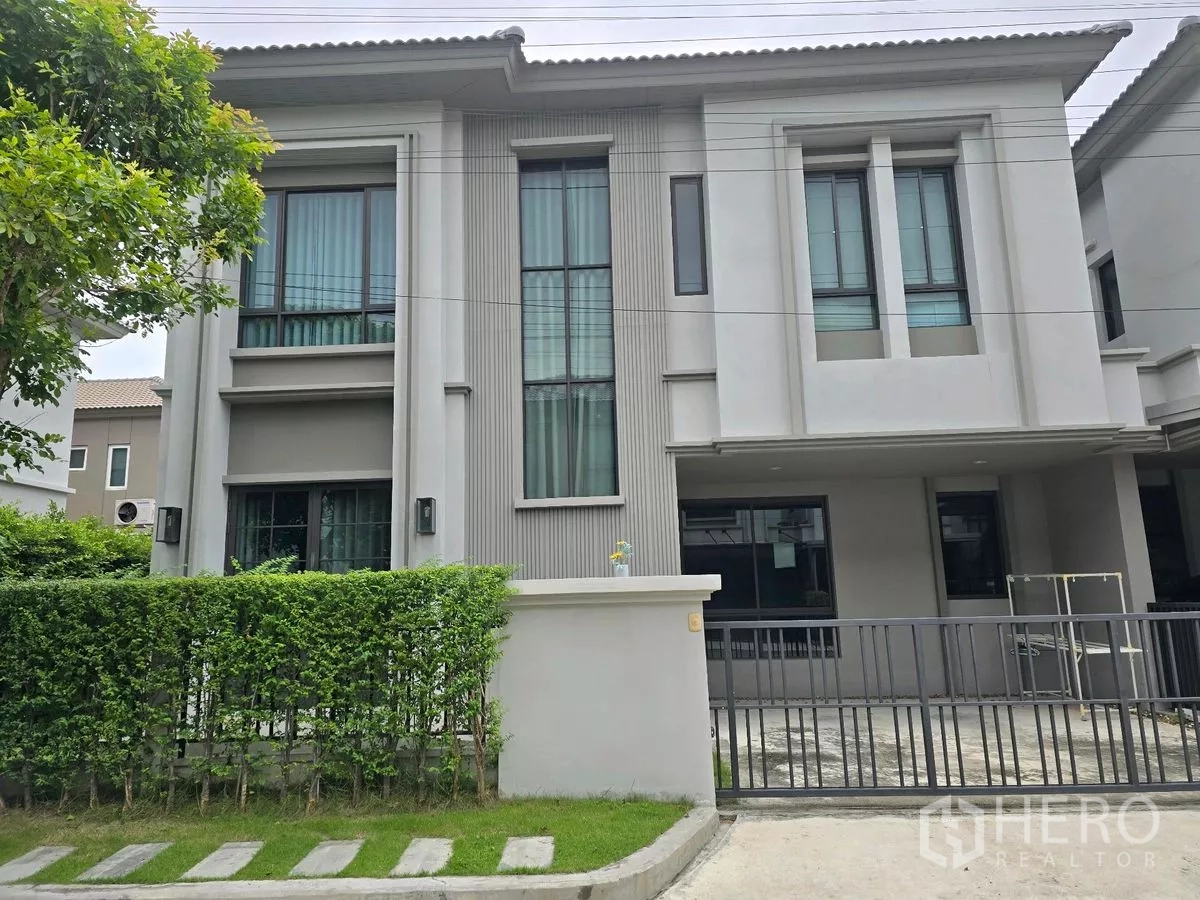 独立式住宅 出租在Khlong Luang, Pathum Thani - 两层现代独栋别墅外观，设大面积落地窗、绿篱与金属滑门，位于空銮巴吞他尼。