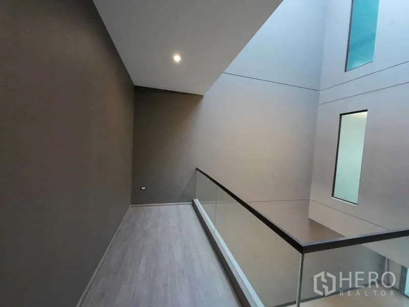 联排别墅 出租或出售在Lat Phrao, Bangkok - 室内回廊，玻璃栏杆俯瞰中庭采光井。