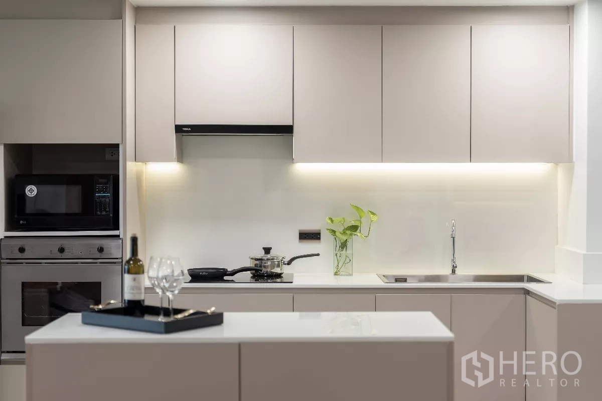 Apartment for rent - Minimalist U-shaped kitchen with glossy white countertops and sink.