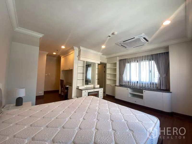 公寓 出租在Watthana, Bangkok - 主卧带梳妆台、开放式书架、窗边柜与嵌入式空调。