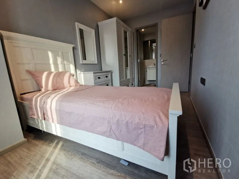 Condominium for rent or sale in Watthana, Bangkok - Cozy third bedroom with single bed, white furniture, wardrobe, and doorway to the bathroom.