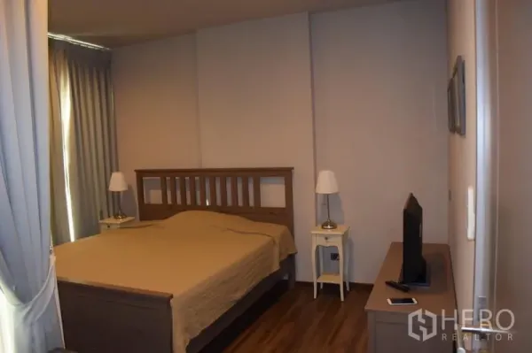 Condominium for rent in Watthana, Bangkok - Cozy bedroom with wooden bedframe, bedside lamps and a TV cabinet.