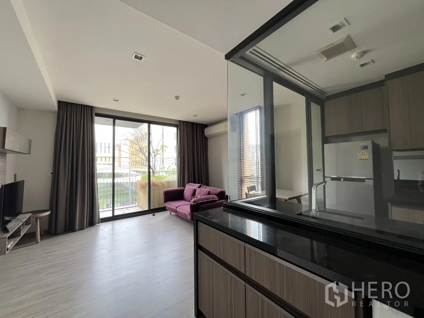 Condominium for rent in Watthana, Bangkok - Open-plan view from the kitchen toward large windows and a balcony planter.