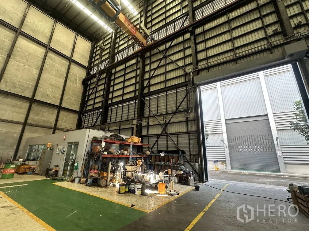 Factory for rent in Lam Luk Ka, Pathum Thani - Workshop zone beside large roller door under tall steel frames.