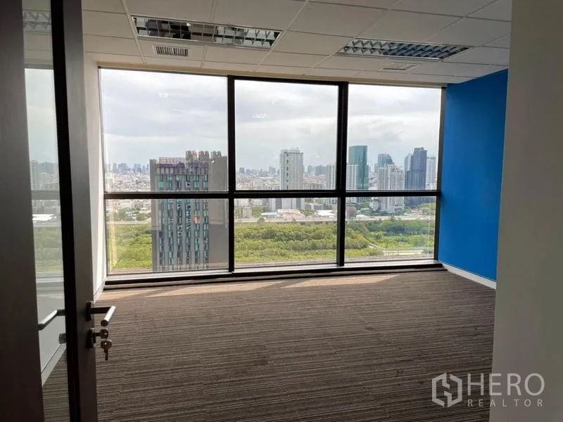 Office Space for rent - Corner private office with a blue accent wall and panoramic city views through large windows.