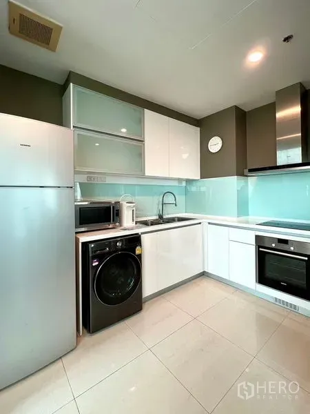คอนโด ให้เช่าในKhlong Toei, Bangkok - ครัวรูปตัวแอลสมัยใหม่ มีเตาอบ ไมโครเวฟ ตู้เย็น และเครื่องซักผ้า ใต้ตู้เงา