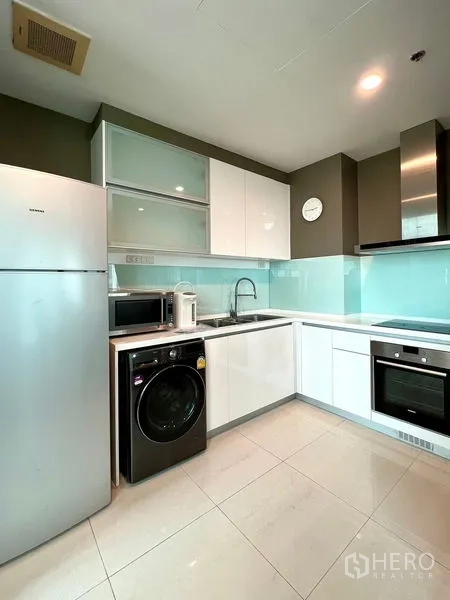 คอนโด ให้เช่าในKhlong Toei, Bangkok - ครัวรูปตัวแอลสมัยใหม่ มีเตาอบ ไมโครเวฟ ตู้เย็น และเครื่องซักผ้า ใต้ตู้เงา