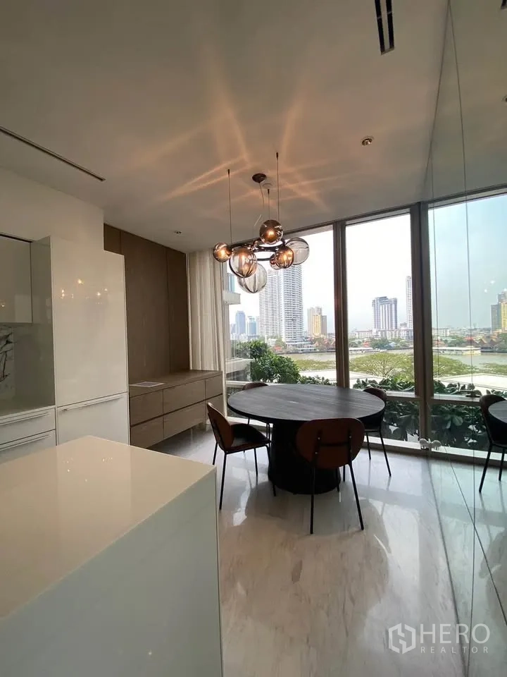 Condominium for rent in Sathon, Bangkok - Bright dining area with a round table and pendant lights beside full-height windows.