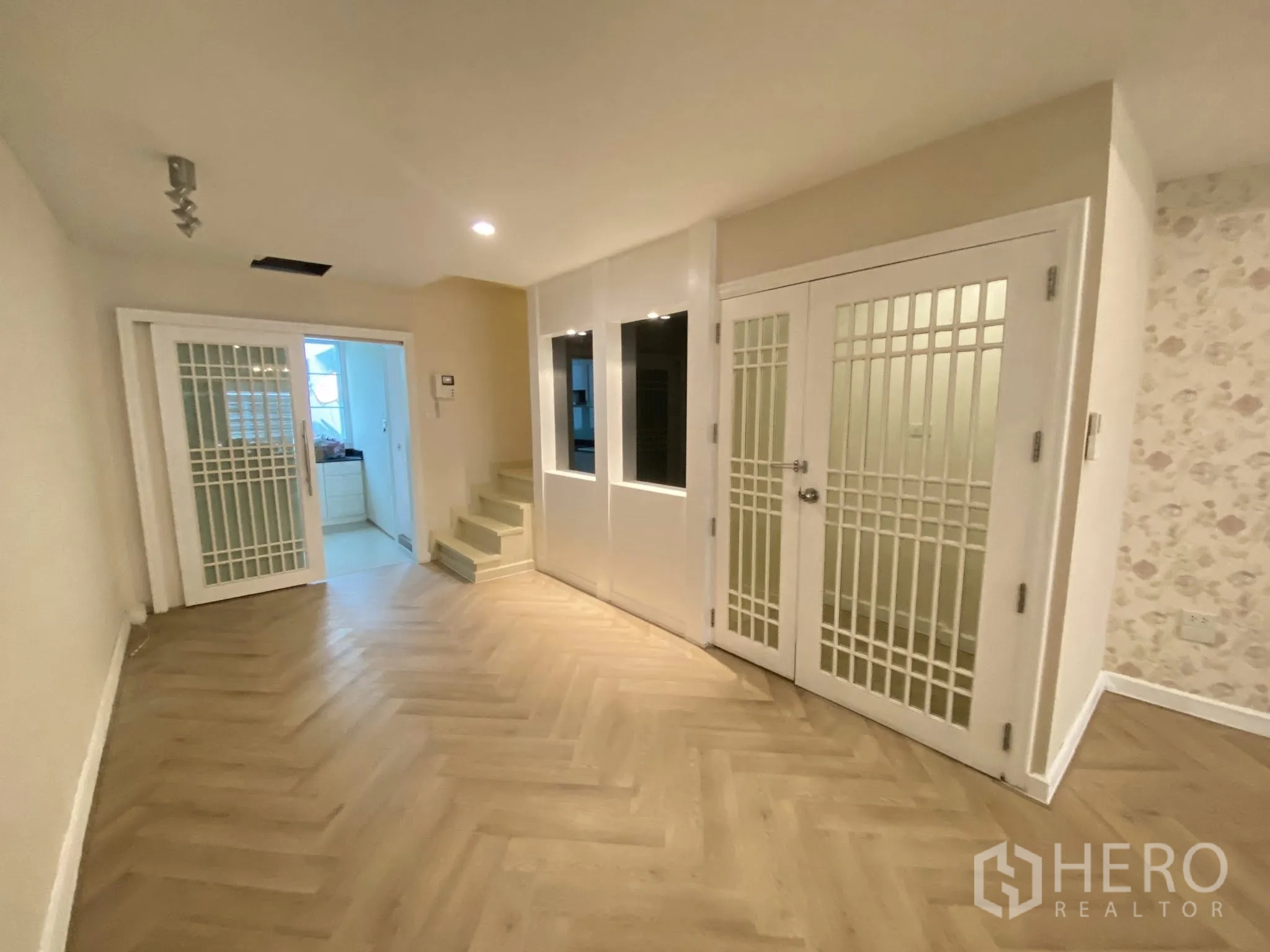 Home Office for rent in Pathum Wan, Bangkok - Multi‑purpose room with herringbone floor, white grid doors, and access to the kitchen.