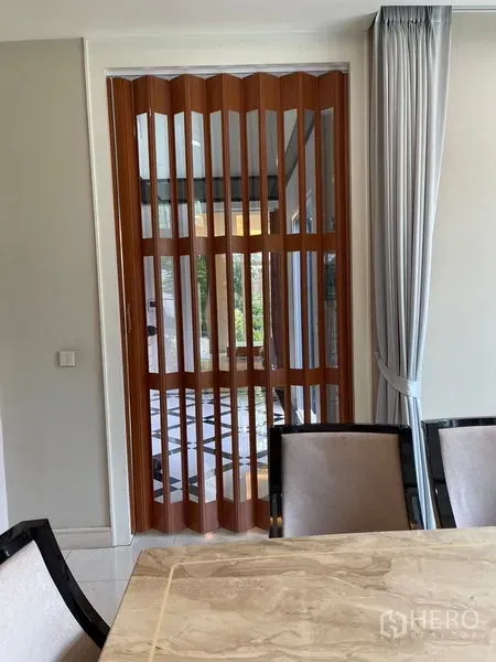 独立式住宅 出租在Bang Phli, Samut Prakan - 餐区旁木质折叠隔断，搭配大理石餐桌与窗帘