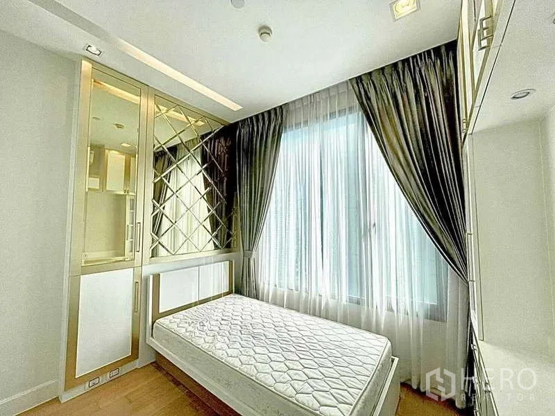 Condominium for rent in Bangkok - Cozy bedroom with bed, sheer curtains and mirrored wall accents.