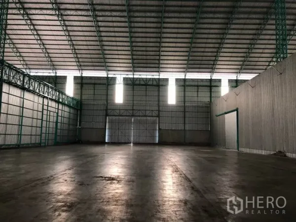 Warehouse for rent in Sai Noi, Nonthaburi - Wide open warehouse floor with vertical skylight panels and large sliding doors.