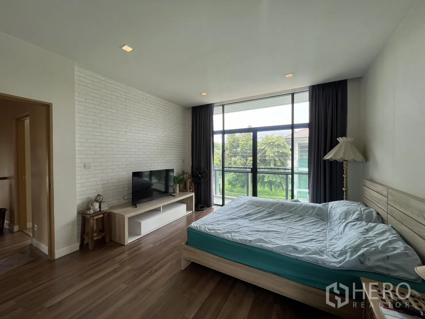 Detached House for rent in Bang Kapi, Bangkok - Master bedroom with king bed, TV console, and floor-to-ceiling windows to balcony.