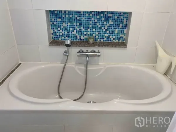 公寓 出租或出售在Phra Khanong, Bangkok - 白色浴缸配手持花洒，墙面蓝色马赛克装饰。