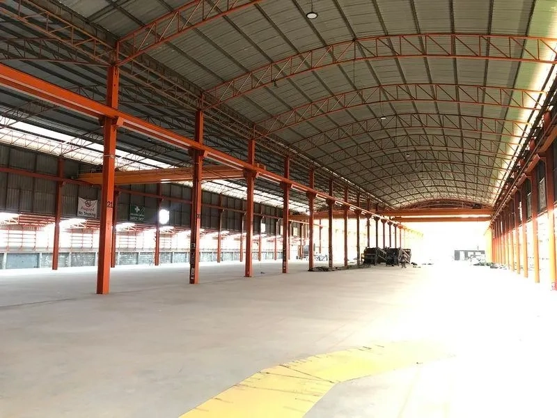 Warehouse for rent in Samut Prakan - Large unobstructed floor area beneath curved roof with rows of steel pillars.