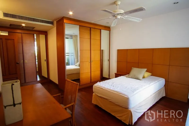 อพาร์ทเมนท์ ให้เช่าในWatthana, Bangkok - ห้องนอนสว่าง พื้นไม้ ผนังพาเนล พัดลมเพดาน ตู้เสื้อผ้าบิลท์อิน และโต๊ะทำงาน