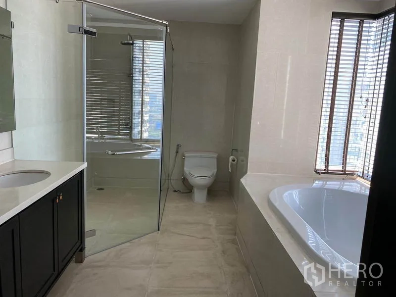 公寓 出租在Khlong Toei, Bangkok - 宽敞浴室，玻璃淋浴间、临窗浴缸、台盆与坐便器。