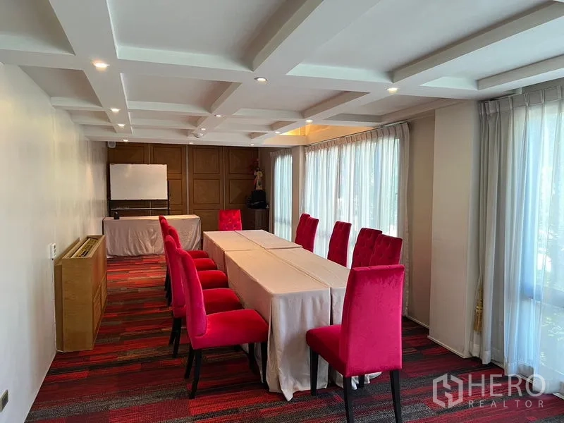 店屋 出租在Suan Luang, Bangkok - 采光明亮的会议室，长桌、红色座椅与落地窗帘。