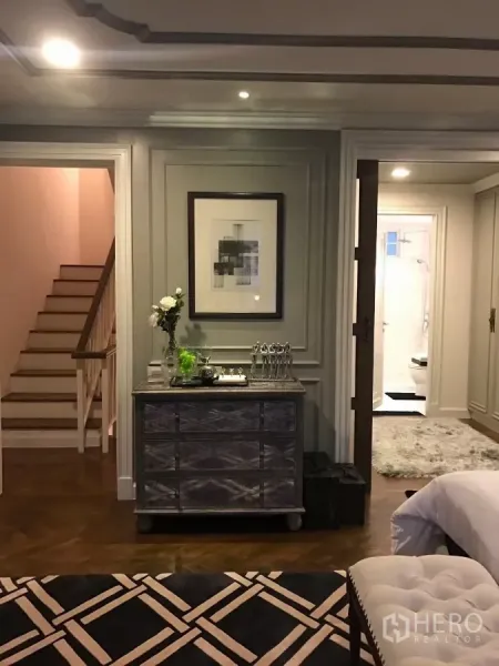 Townhouse for sale in Watthana, Bangkok - Suite landing with staircase, dresser and soft lighting leading toward a bathroom.