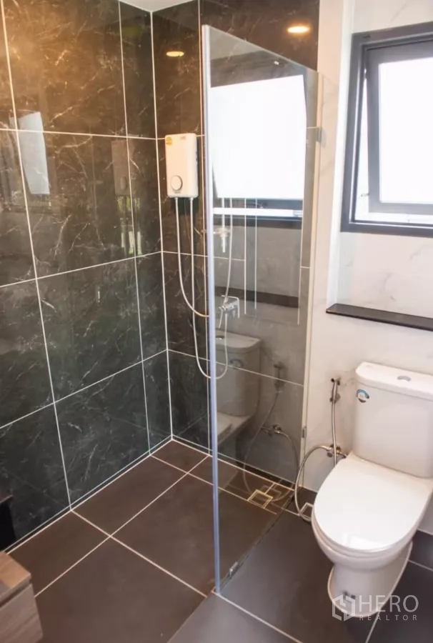 Detached House for rent in Bang Phli, Samut Prakan - Bathroom with glass shower enclosure, dark tiles and a modern toilet.