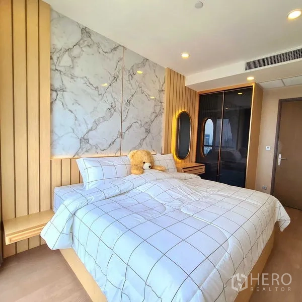 Condominium for rent in Bang Rak, Bangkok - Bedroom with large bed, marble feature wall and floor-to-ceiling window view.